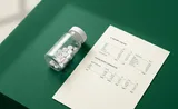 A small bottle of white pills sitting on a green desk next to a printed financial comparables sheet, evoking Kepler as a painkiller for financial analysts.